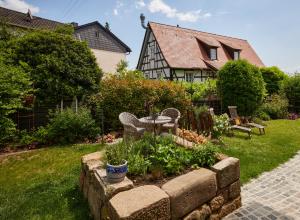 a garden with a table and chairs in front of a house at Winzerlodge, Wohnung Hatzelberg in Gleiszellen-Gleishorbach +19 photos