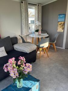 a living room with a couch and a table with flowers at NEU Chalet Wattenmeerblick 2026 in Westerland