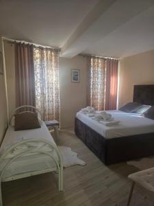 a bedroom with two beds and a chair and windows at Nada's room with terrace in Kotor
