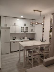 a kitchen with white cabinets and a table and chairs at Apartment 10 in Inđija +12 photos