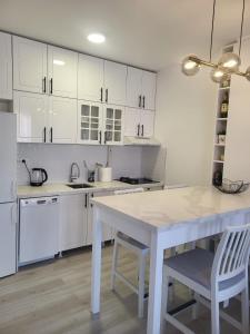 a kitchen with white cabinets and a white table and chairs at Apartment 10 in Inđija