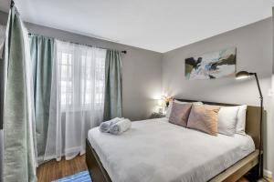 a bedroom with a bed with white sheets and a window at New 3BDRM Centrally Located Free Parking AC in Buffalo