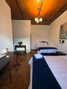 a room with two beds and a table and a desk at Hotel y Restaurante Posada Real in Quetzaltenango