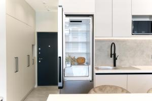 a kitchen with white cabinets and a black refrigerator at Designer Studio - Rooftop - Sea View - Arcadia 200m in Odesa