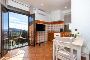 a kitchen with a dining table and a balcony at Hotel Rural Sierra Tejeda in Alcaucín