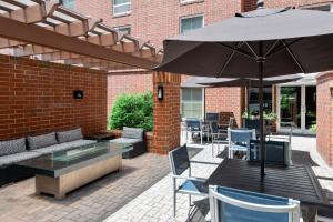 a patio with an umbrella and a table and chairs at Hampton Inn & Suites Charlottesville at the University in Charlottesville