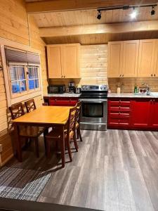 a kitchen with a wooden table and red cabinets at Terrawoods Pine Cottage in Parry Sound