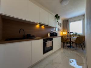 a kitchen with white cabinets and a dining room with a table at The Elegant Hideaway in Šurany