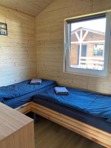 two beds in a cabin with a window at Domki pod Dębem in Wilkasy