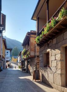 a street in a town with flowers on the side of a building at Casa Rural Maria in Molinaseca
