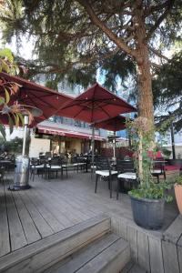 a patio with tables and chairs and a tree at Hotel Apart Odeon in Durrës