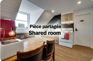 a kitchen with a wooden table and a shared room at Chambre 304 de l'hôtel Victoria confortable et moderne in Saint-Pascal