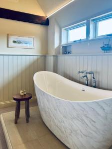 a large white bath tub in a bathroom at Dingle Marsh Barns in Dunwich +37 photos
