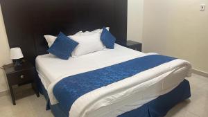 a bedroom with a large bed with blue and white pillows at شقق مساكن الراية المخدومه in Al Khobar