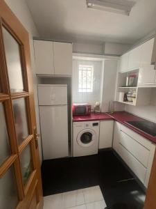 a small kitchen with white cabinets and a washing machine at La Morada del Jucar in Cuenca