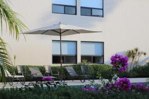 a patio with chairs and an umbrella and purple flowers at Casa Begonias Hotel mas Villas in Jiutepec +78 photos