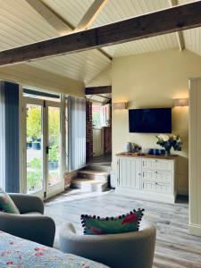 a living room with a flat screen tv on the wall at Dingle Marsh Barns in Dunwich