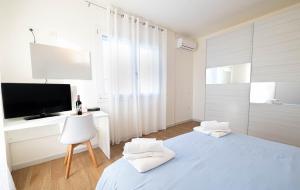 a white bedroom with a bed and a tv at Corona Guest House in Sestu