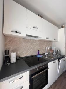 a kitchen with white cabinets and a black counter top at Apartman Karmen in Brodarica +5 photos