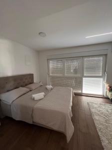 a bedroom with a large bed and a large window at Apartman Karmen in Brodarica