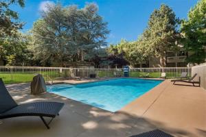 a swimming pool in a yard with chairs and a fence at SureStay Plus Hotel by Best Western Reno Airport in Reno