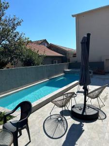 a patio with chairs and an umbrella and a pool at Bohemian Beach Retreat in Donja Lastva