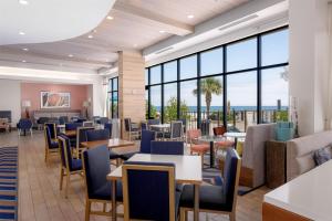 a waiting room with tables and chairs and windows at Hampton Inn & Suites - Orange Beach in Orange Beach