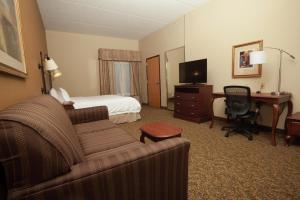 a hotel room with a couch and a bed and a desk at Hampton Inn Oneonta in Oneonta