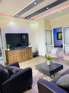 a living room with a tv and a couch and a table at Zac Mbao appartement meuble in Mbaw