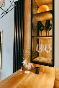 a shelf with wine glasses on a wooden table at Golden Luxury Suite in Nowy Dwór Mazowiecki