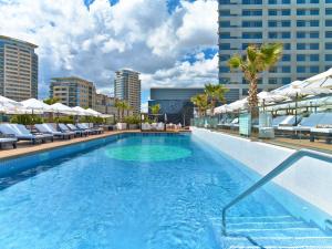 a large swimming pool with chairs and umbrellas on a building at Hilton Diagonal Mar Barcelona in Barcelona