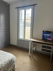 a bedroom with a desk with a television and a window at Studio à 350m de la gare in Tours