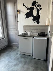 a kitchen with a sink and a witch stencil on the wall at Studio à 350m de la gare in Tours