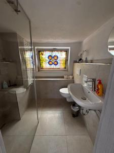 a bathroom with a sink and a toilet and a window at Bay Fewo in Rosenheim