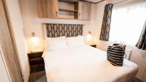 a small bedroom with a bed and a window at 3. Supreme OD 2 Caravan with Decking in Ringwood +2 photos