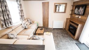 a living room with a couch and a fireplace at 6. Supreme OD 2 Caravan with Decking in Ringwood