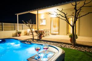two glasses of wine sitting on a table next to a hot tub at GARDEN HOUSE, Kalamaki in Tympáki