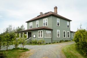 a green house with a roof on a dirt road at Woodside Farm Country Inn in Sooke
