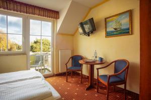 a hotel room with a bed and a table and chairs at Hotel Ostseeblick - direkt hinter den Dünen in Karlshagen