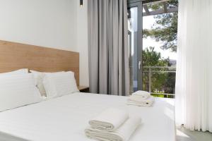 a bedroom with a white bed with towels on it at Pine Suites in Potos
