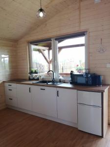 a kitchen with white cabinets and a sink and a window at Domki pod Dębem in Wilkasy