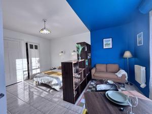 a bedroom with blue walls and a bed and a couch at Nuit Panoramique - Studio - Wifi - 2 pers in Châtel-Guyon