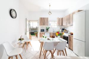 a kitchen with a table and chairs and a white refrigerator at GARDEN HOUSE, Kalamaki in Tympáki