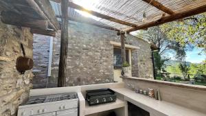 an outdoor kitchen with a stove and a stone wall at L'Ape in Fogliano