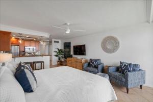 a bedroom with a bed and two chairs and a kitchen at Lahaina203 in Lahaina