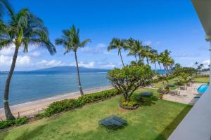 a view of a beach with palm trees and chairs at Lahaina203 in Lahaina