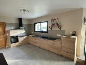 a kitchen with wooden cabinets and a sink and a window at GITE DE L'ORCHIDÉE P M r in Locmaria-Grand-Champ