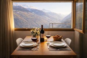 a table with two glasses of wine and a window at Maison d'Hortense - Chalet le Renard in Hérémence