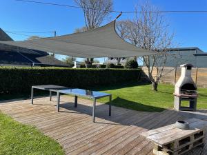 a picnic table with a covering over it on a deck at GITE DE L'ORCHIDÉE P M r in Locmaria-Grand-Champ