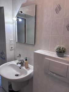a white bathroom with a sink and a mirror at Ferienwohnung in Hackenheim